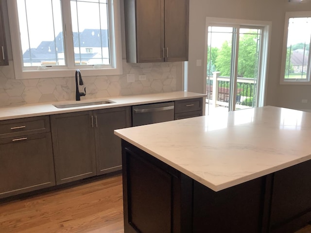 12415 Foxborough Dr, Mokena, IL 60448 - kitchen featuring dishwasher, light wood-style flooring, decorative backsplash, a center island, and light stone countertops