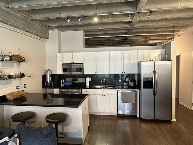 811 S Lytle St Unit 108, Chicago, IL 60607 - kitchen with stainless steel appliances, track lighting, dark countertops, dark wood finished floors, and white cabinets