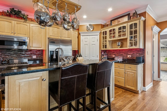 24650 Lincolnway St, Plainfield, IL 60544 - kitchen featuring appliances with stainless steel finishes, a kitchen breakfast bar, ornamental molding, glass insert cabinets, and decorative backsplash