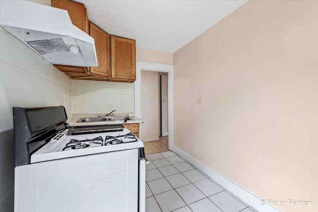 566 Raymond St, Elgin, IL 60120 - kitchen with white range with gas stovetop, ventilation hood, light countertops, brown cabinets, and light tile patterned floors
