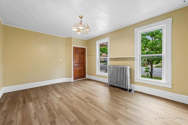 566 Raymond St, Elgin, IL 60120 - spare room with radiator, a chandelier, and light wood-style floors