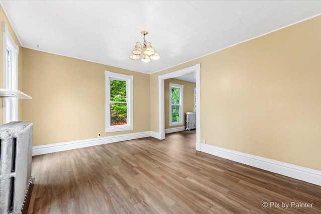 566 Raymond St, Elgin, IL 60120 - unfurnished living room featuring radiator, a chandelier, and wood finished floors