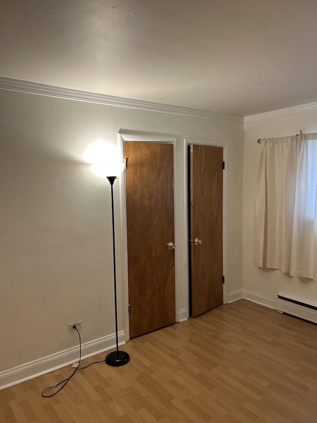 214 S Oak Park Ave Unit 2, Oak Park, IL 60302 - unfurnished bedroom featuring light wood finished floors, crown molding, a baseboard radiator, and two closets