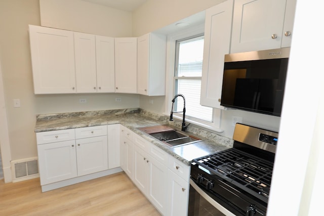507 Grant Ave, Joliet, IL 60433 - kitchen with stainless steel appliances, white cabinetry, light wood finished floors, and light countertops