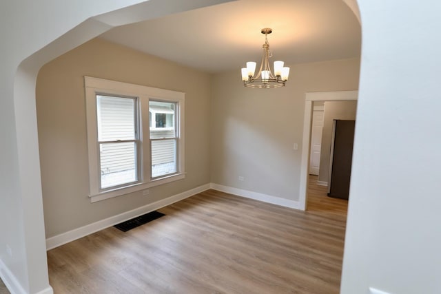 507 Grant Ave, Joliet, IL 60433 - spare room featuring a chandelier, light wood-style floors, and arched walkways