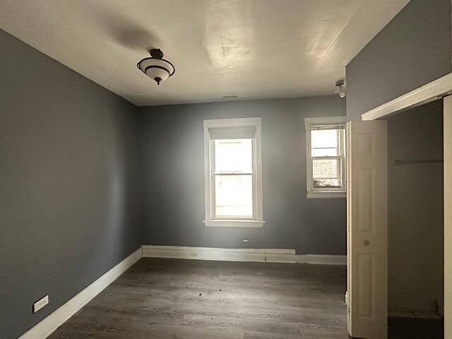 4131 N Monticello Ave, Chicago, IL 60618 - unfurnished bedroom featuring dark wood-style flooring and baseboards