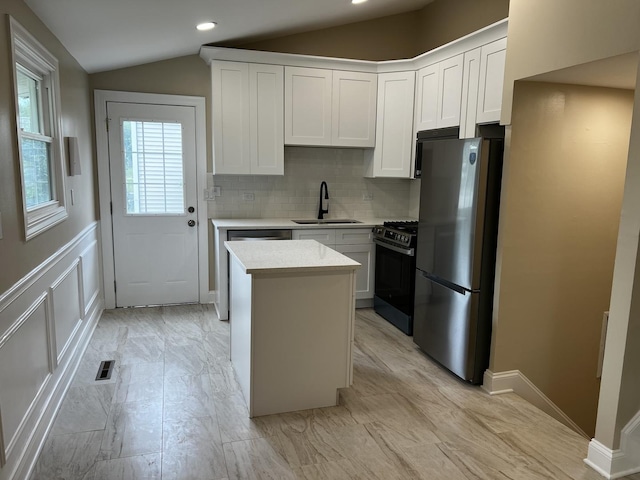 805 Monroe Ave, Carpentersville, IL 60110 - kitchen featuring appliances with stainless steel finishes, vaulted ceiling, light countertops, a kitchen island, and tasteful backsplash
