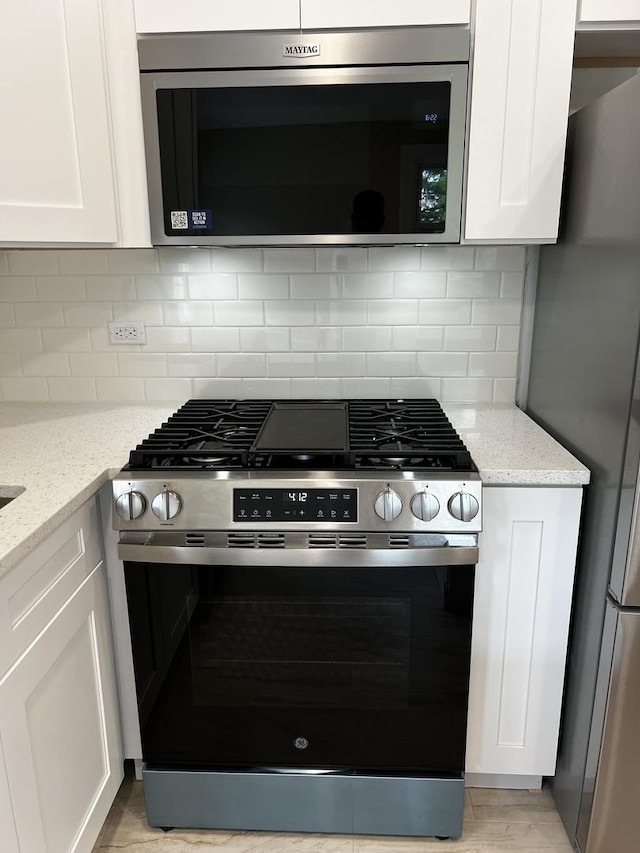 805 Monroe Ave, Carpentersville, IL 60110 - kitchen with stainless steel appliances, white cabinets, light stone countertops, and decorative backsplash