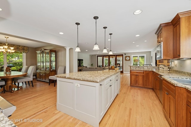 235 Valley Rd, Trout Valley, IL 60013 - kitchen featuring open floor plan, light wood-style floors, brown cabinetry, appliances with stainless steel finishes, and decorative light fixtures