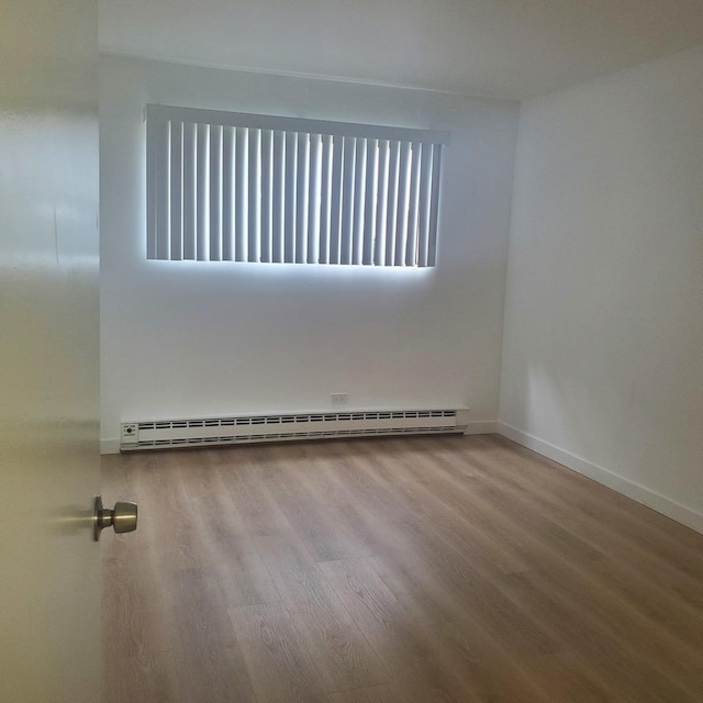 5117 N E River Rd Unit 1A, Chicago, IL 60656 - spare room featuring a baseboard heating unit and wood finished floors