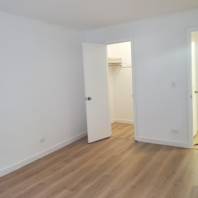 5117 N E River Rd Unit 1A, Chicago, IL 60656 - unfurnished bedroom featuring light wood-style flooring, a closet, and a wall unit AC