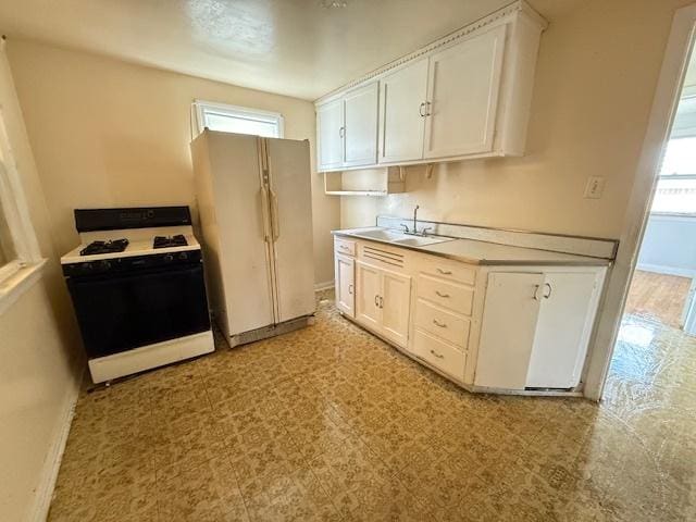 2025 Marshall Pkwy, Waukegan, IL 60085 - kitchen featuring gas range, freestanding refrigerator, plenty of natural light, and white cabinetry