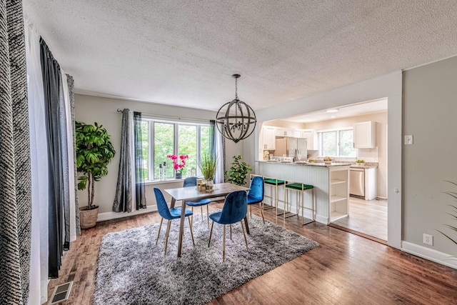 1502 N 34th Ave, Melrose Park, IL 60160 - dining area featuring a chandelier, a textured ceiling, healthy amount of natural light, and light wood finished floors