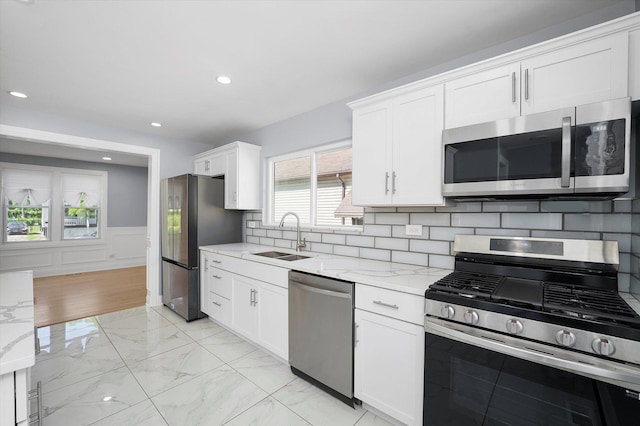 536 E 155th St, Phoenix, IL 60426 - kitchen featuring stainless steel appliances, light marble finish floors, white cabinets, light stone counters, and a wainscoted wall