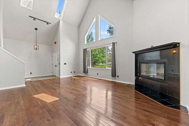 4293 W Rockton Rd, Rockton, IL 61072 - unfurnished living room with high vaulted ceiling, rail lighting, hardwood / wood-style flooring, a fireplace, and a skylight