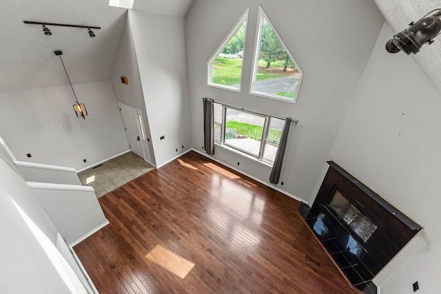 4293 W Rockton Rd, Rockton, IL 61072 - unfurnished living room featuring high vaulted ceiling, wood-type flooring, rail lighting, a fireplace, and a textured ceiling
