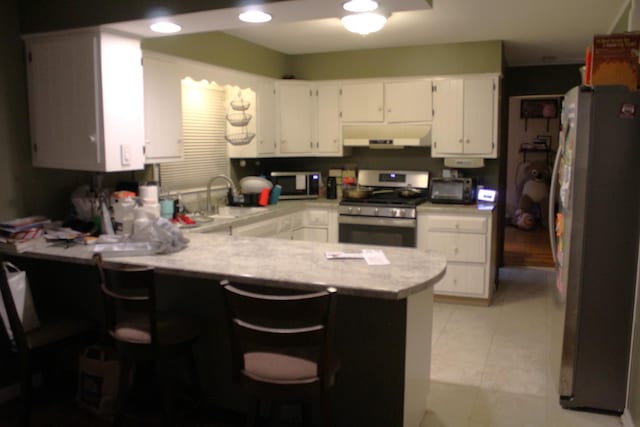 1254 Blackhawk Dr, Elgin, IL 60120 - kitchen featuring appliances with stainless steel finishes, a peninsula, light countertops, white cabinetry, and extractor fan
