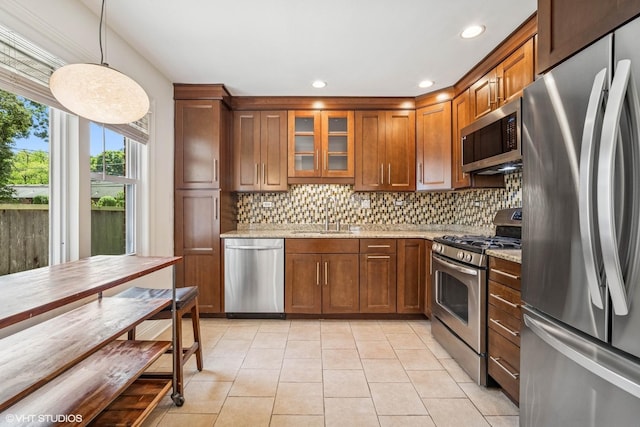 630 Wesley Dr, Park Ridge, IL 60068 - kitchen featuring appliances with stainless steel finishes, decorative backsplash, light tile patterned floors, light stone countertops, and brown cabinetry