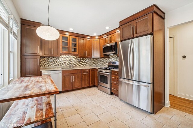 630 Wesley Dr, Park Ridge, IL 60068 - kitchen with appliances with stainless steel finishes, decorative backsplash, light tile patterned flooring, light stone countertops, and glass insert cabinets