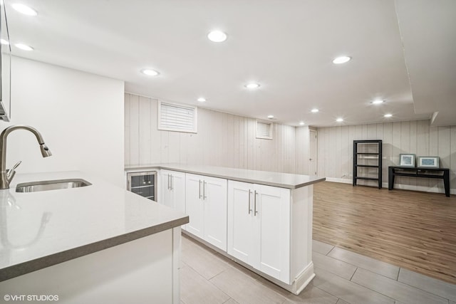 630 Wesley Dr, Park Ridge, IL 60068 - kitchen with white cabinets, a peninsula, wood walls, light countertops, and beverage cooler