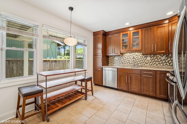 630 Wesley Dr, Park Ridge, IL 60068 - kitchen featuring appliances with stainless steel finishes, backsplash, brown cabinets, light tile patterned floors, and hanging light fixtures