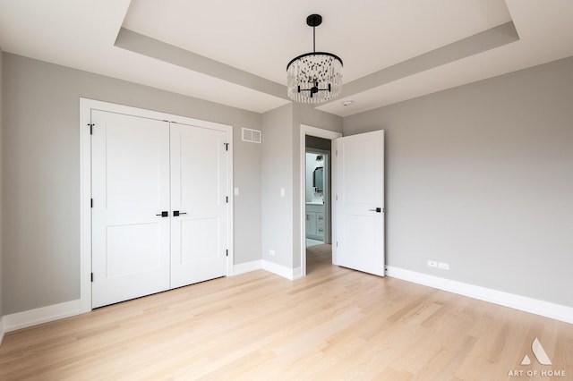 77371/2 Nashville Ave, Burbank, IL 60459 - unfurnished bedroom with light wood-type flooring, a chandelier, a closet, and a tray ceiling