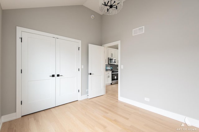 77371/2 Nashville Ave, Burbank, IL 60459 - unfurnished bedroom featuring high vaulted ceiling, light wood-type flooring, a chandelier, and a closet