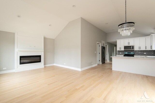 77371/2 Nashville Ave, Burbank, IL 60459 - kitchen with black appliances, vaulted ceiling, a chandelier, white cabinets, and a glass covered fireplace