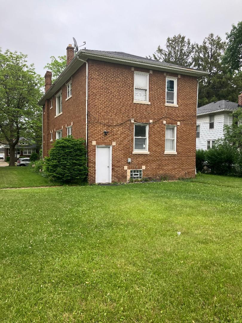 1532 N Ave, Waukegan, IL 60085 - view of side of property featuring a chimney, brick siding, and a lawn