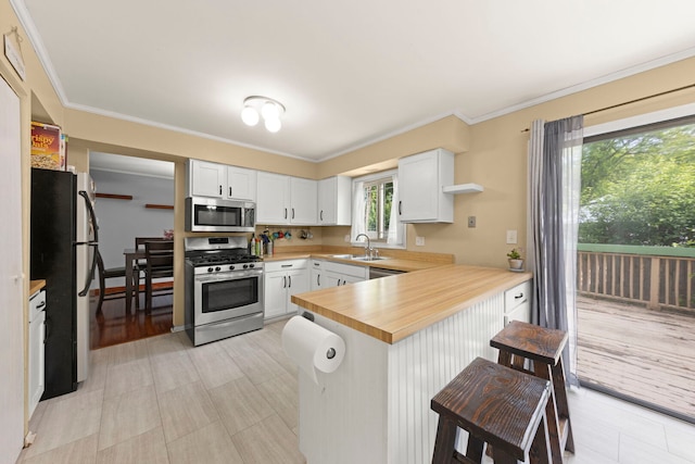 1004 Evergreen Dr, Carol Stream, IL 60188 - kitchen featuring stainless steel appliances, a peninsula, white cabinetry, crown molding, and a kitchen bar