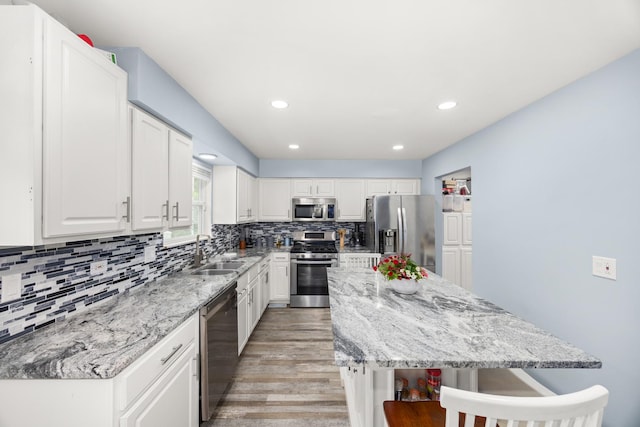 2853 Forestview Dr, Carpentersville, IL 60110 - kitchen featuring stainless steel appliances, a center island, light wood-style floors, white cabinetry, and tasteful backsplash