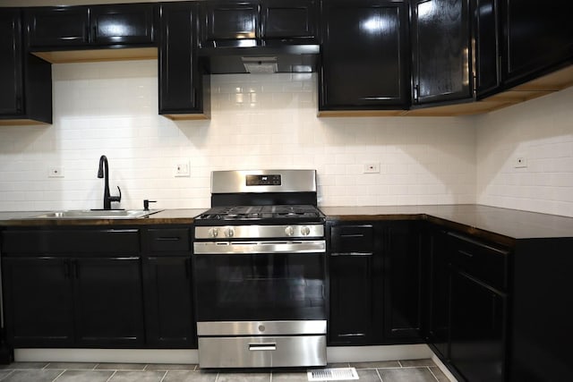 8346 S Baltimore Ave, Chicago, IL 60617 - kitchen featuring gas range, dark cabinets, under cabinet range hood, decorative backsplash, and dark countertops