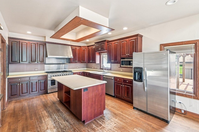 18229 Riegel Rd, Homewood, IL 60430 - kitchen featuring appliances with stainless steel finishes, wall chimney exhaust hood, light countertops, a center island, and wood finished floors