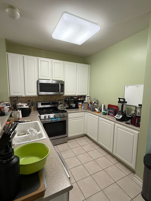 352 Bay Dr, Itasca, IL 60143 - kitchen with appliances with stainless steel finishes, white cabinetry, light tile patterned floors, decorative backsplash, and light countertops
