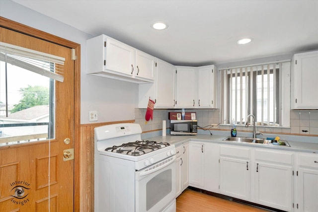 5716 W 64th Pl, Chicago, IL 60638 - kitchen featuring white range with gas cooktop, stainless steel microwave, light countertops, white cabinets, and a wainscoted wall