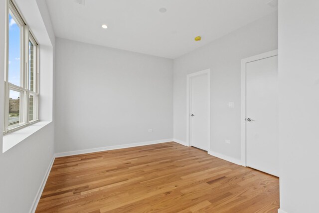 7239 S Exchange Ave, Chicago, IL 60649 - unfurnished bedroom featuring multiple windows, light wood finished floors, and recessed lighting
