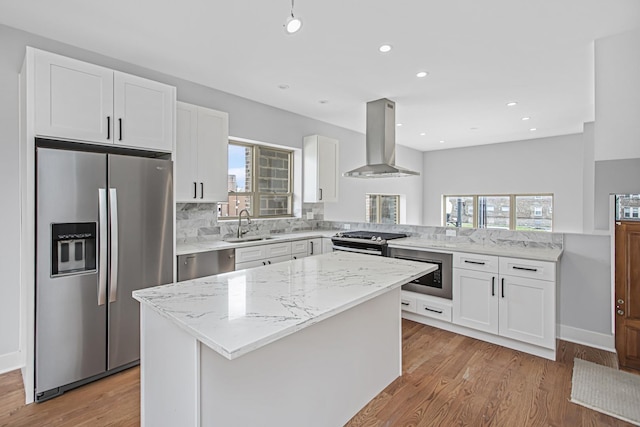 7239 S Exchange Ave, Chicago, IL 60649 - kitchen featuring island range hood, appliances with stainless steel finishes, a peninsula, backsplash, and light wood-style flooring