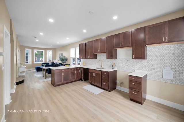 5029 W Superior St, Chicago, IL 60644 - kitchen featuring light wood-style flooring, a peninsula, dark brown cabinets, decorative backsplash, and recessed lighting