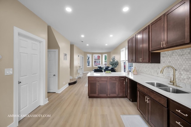 5029 W Superior St, Chicago, IL 60644 - kitchen featuring light wood finished floors, decorative backsplash, light countertops, a peninsula, and dark brown cabinetry