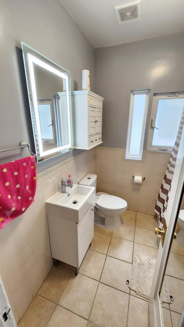 8127 S Blackstone Ave, Chicago, IL 60619 - full bath with tile walls, vanity, tile patterned flooring, a wainscoted wall, and a shower