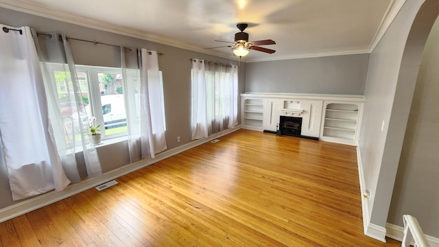 8127 S Blackstone Ave, Chicago, IL 60619 - unfurnished living room featuring light wood-style floors, a fireplace with raised hearth, a ceiling fan, crown molding, and arched walkways