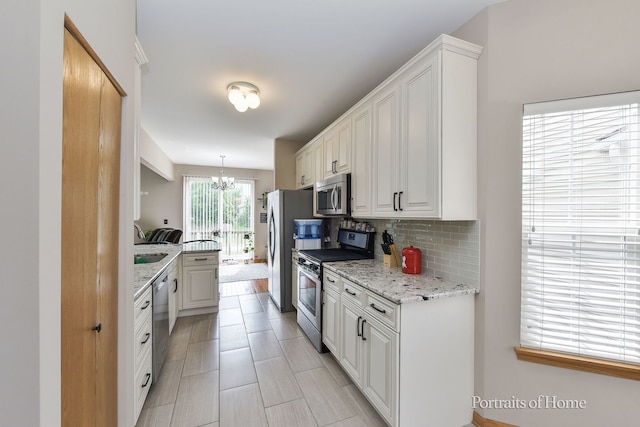 497 Le Moyne Ave, Romeoville, IL 60446 - kitchen featuring stainless steel appliances, decorative backsplash, a chandelier, white cabinetry, and light stone counters
