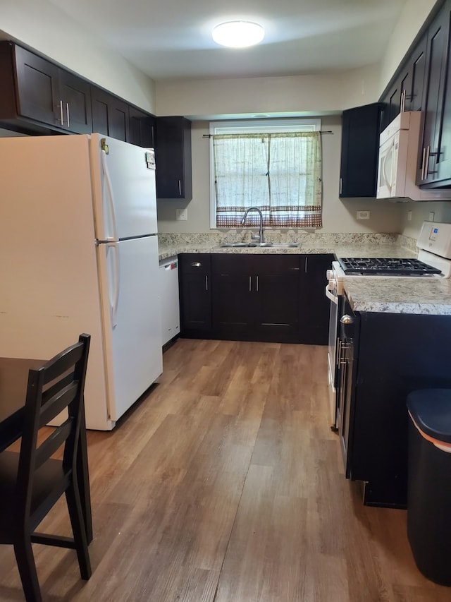 4917 Prairie Ave, Mchenry, IL 60050 - kitchen featuring white appliances, dark cabinetry, light stone counters, and light wood-style flooring