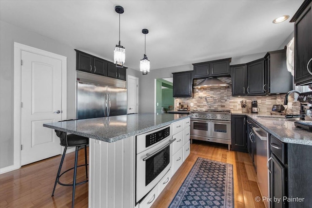 911 Water Stone Way, Malta, IL 60150 - kitchen featuring premium appliances, light wood-style floors, a center island, backsplash, and dark stone counters