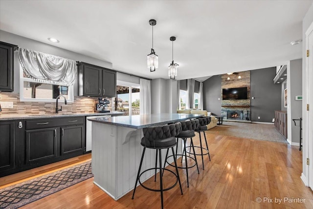 911 Water Stone Way, Malta, IL 60150 - kitchen featuring stainless steel dishwasher, light wood-style flooring, a large fireplace, a kitchen breakfast bar, and recessed lighting