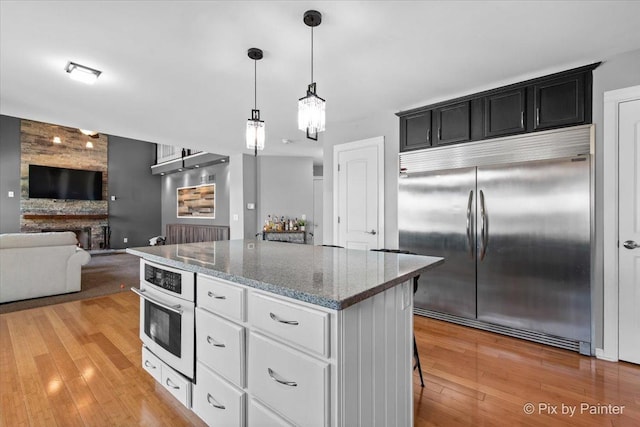 911 Water Stone Way, Malta, IL 60150 - kitchen featuring stainless steel appliances, stone countertops, a kitchen island, and light wood finished floors