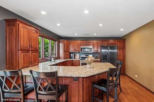 9228 S 55th Ct, Oak Lawn, IL 60453 - kitchen featuring stainless steel appliances, a peninsula, light stone counters, recessed lighting, and light wood finished floors