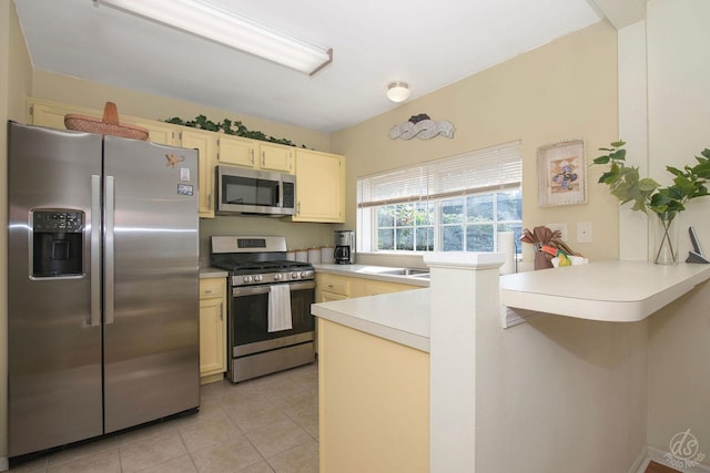 1288 Seabury Cir, Carol Stream, IL 60188 - kitchen featuring appliances with stainless steel finishes, a peninsula, light countertops, light tile patterned floors, and cream cabinets