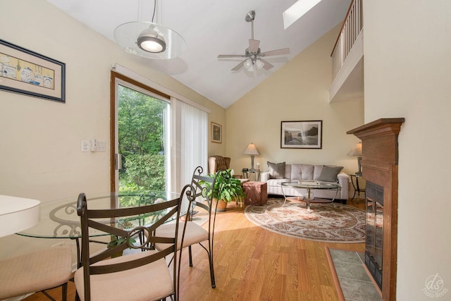 1288 Seabury Cir, Carol Stream, IL 60188 - dining room featuring wood finished floors, a fireplace with flush hearth, a ceiling fan, high vaulted ceiling, and a skylight