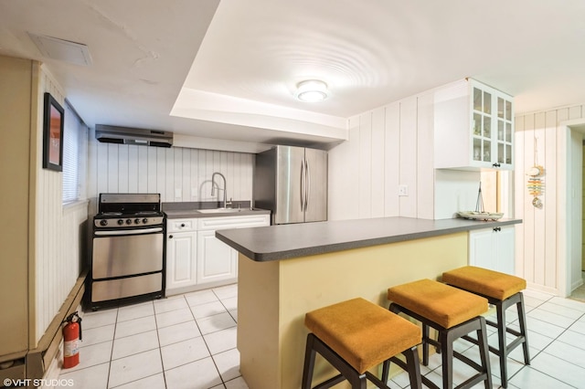 1116 W N Shore Ave Unit 2, Chicago, IL 60626 - kitchen featuring stainless steel appliances, dark countertops, light tile patterned floors, glass insert cabinets, and a kitchen bar
